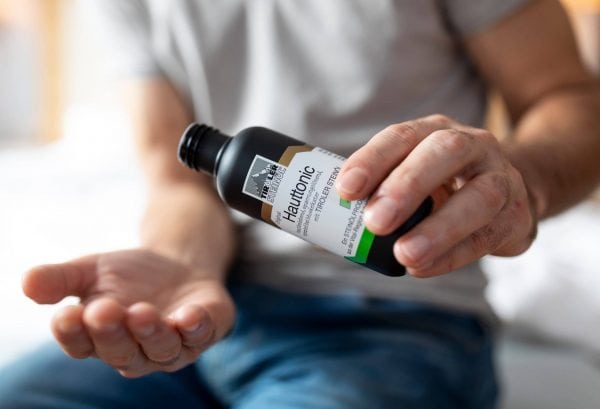 Hauttonic mit TIROLER STEINÖL Anwendung Mann gibt Hautpflegeprodukt in die Hand