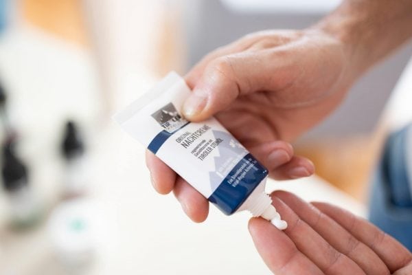 Hände drücken eine Tube Creme aus